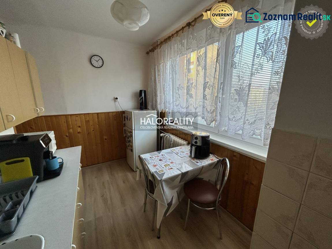 Küche mit Holzdekor in einer 2-Zimmer-Wohnung. Feine Vorhänge, Esstisch, Kaffeemaschine.