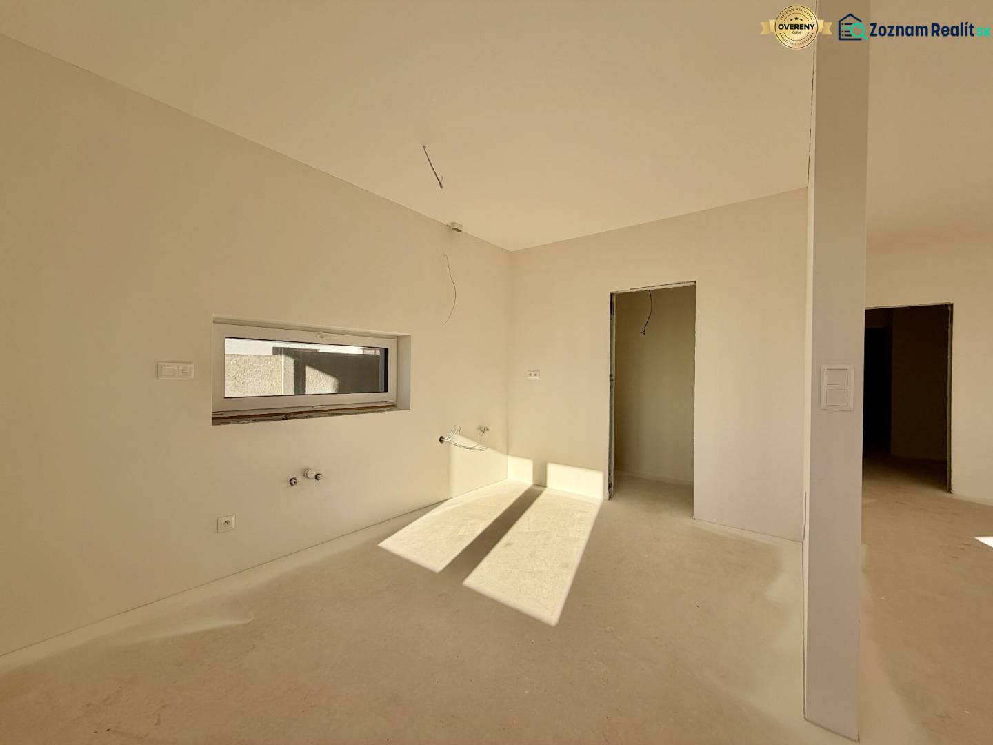 Ein geräumiger, unmöblierter Raum in einem Einfamilienhaus mit einem Fenster und einer Tür ohne Boden.