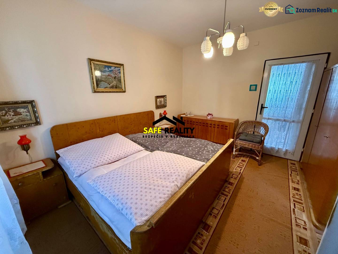 Schlafzimmer in einer 2-Zimmer-Wohnung mit gepolstertem Bett, Teppichboden und dekorativen Bildern.