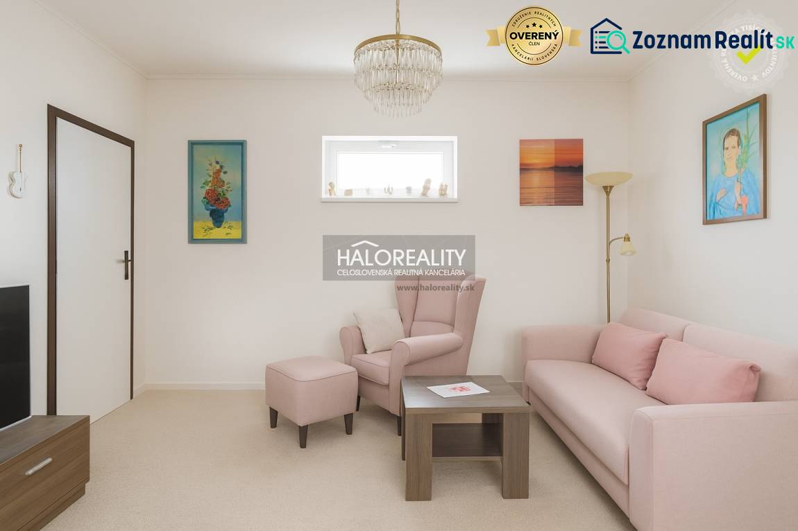 Wohnzimmer mit pastellfarbenem Sofa und Sessel in einem Einfamilienhaus, dekorative Bilder an den Wänden.