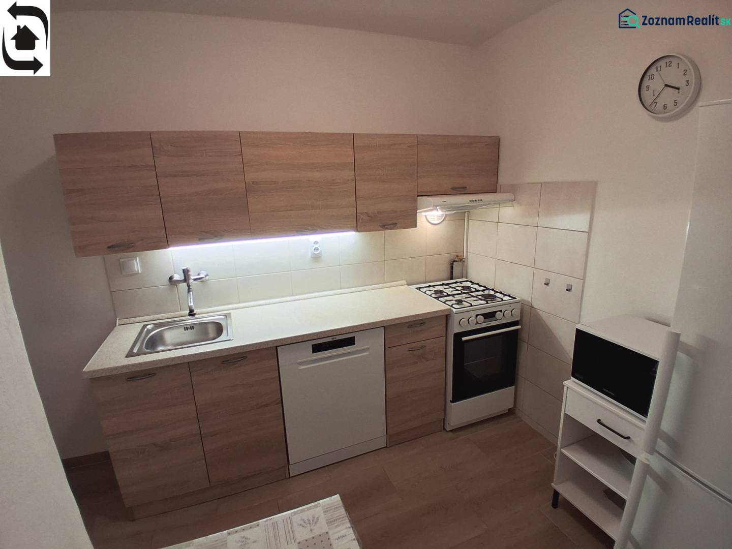 Küche in einer 3-Zimmer-Wohnung mit Küchenzeile, Herd, Geschirrspüler und Bodenbelag in Holzoptik.