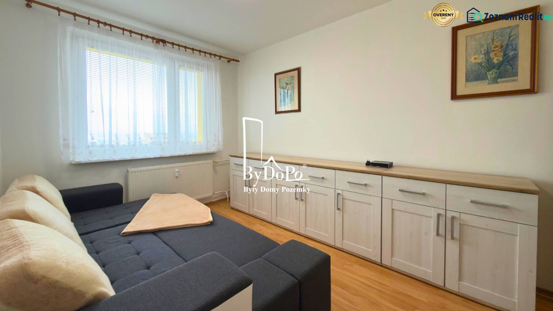 Ein Zimmer mit einem Sofa, Möbeln und einem Boden in Holzoptik in einer 3-Zimmer-Wohnung.