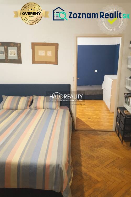 Schlafzimmer in einer 3-Zimmer-Wohnung mit Holzboden und bunter Bettwäsche.