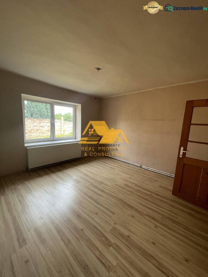 Ein Zimmer mit einem großen Fenster und einem Boden in Holzoptik in einem Einfamilienhaus.