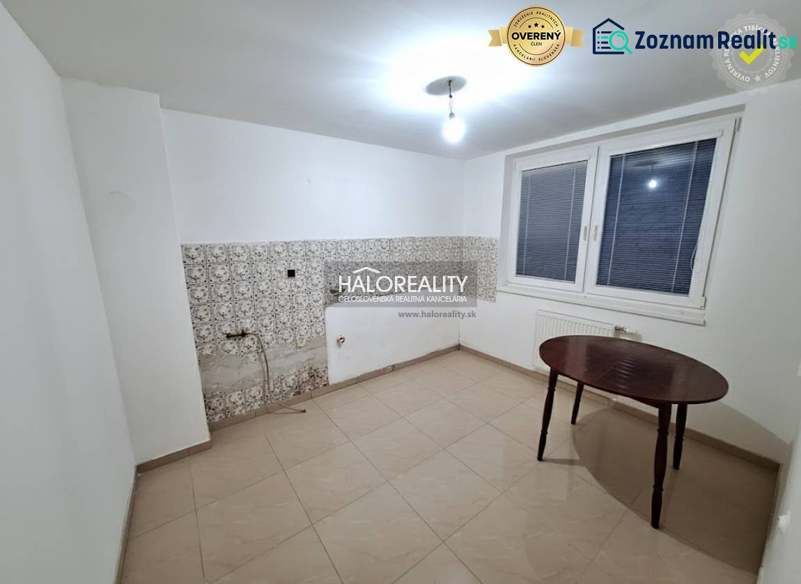 Ein Zimmer in einem Einfamilienhaus mit weißen Wänden, einem Fenster und Fliesen.