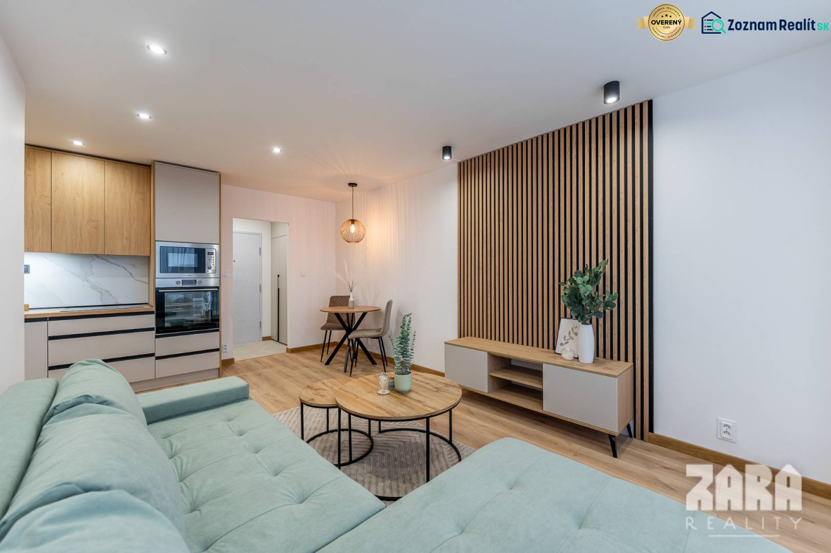 Wohnzimmer in einer 2-Zimmer-Wohnung mit Küchenzeile und Holzboden.