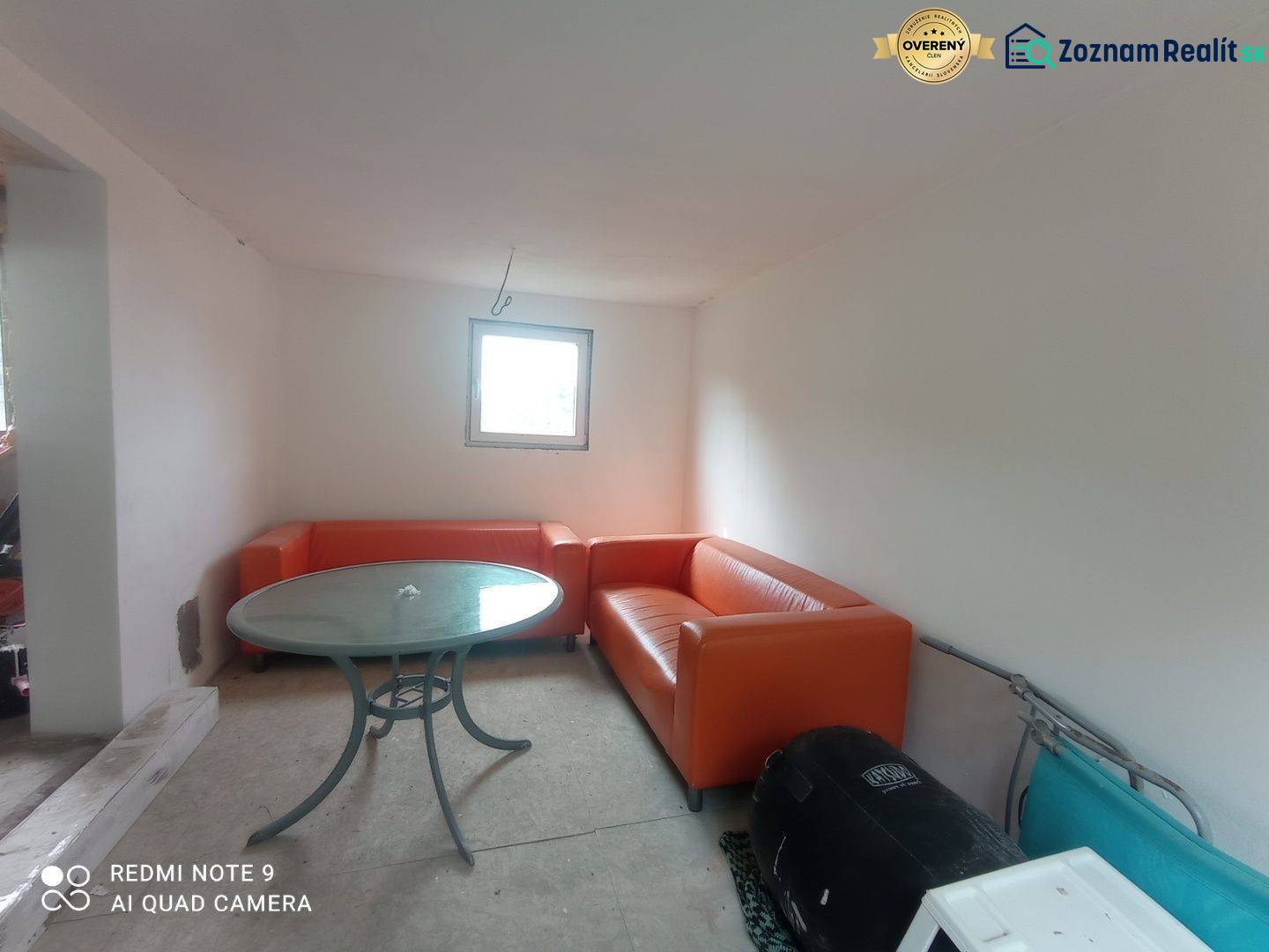 Orangefarbene Sofas und ein runder Tisch ergänzen den Raum in einer Hütte mit weißen Wänden.