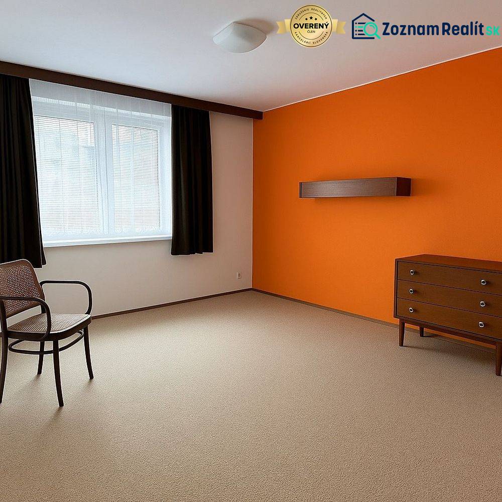 Ein Zimmer mit einer orangefarbenen Wand, Möbeln, einem Fenster und einem Teppichboden in einem Einfamilienhaus.