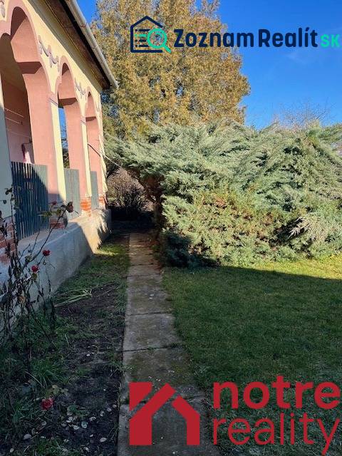 Ein Einfamilienhaus in Tomášovce mit einem Vorgarten und einem großen Baum am Gehweg.
