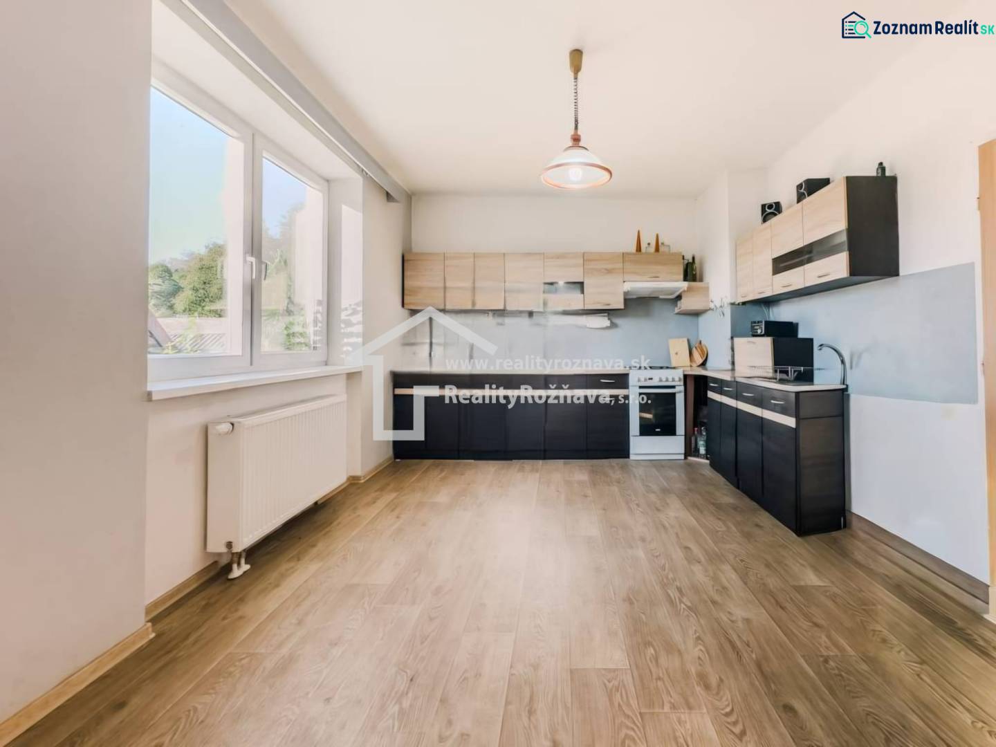 Küche in einem Einfamilienhaus mit Holzboden und großem Fenster.