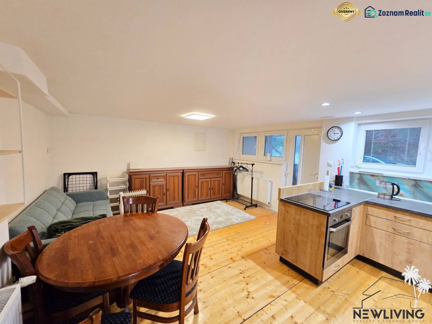 Wohnzimmer in einer Einzimmerwohnung mit Holzboden, Sofa und Esstisch.