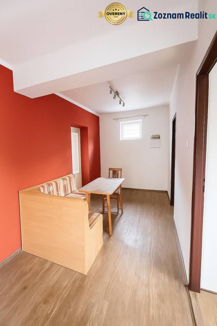 Esszimmer in einem Einfamilienhaus mit roter Wand und Boden in Holzoptik.