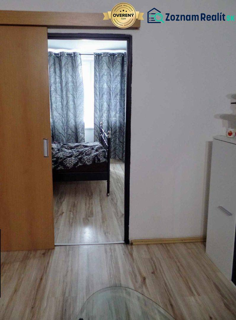 Innenraum mit Holzboden, Schiebetüren und schwarz-weißen Vorhängen in einer 3-Zimmer-Wohnung.