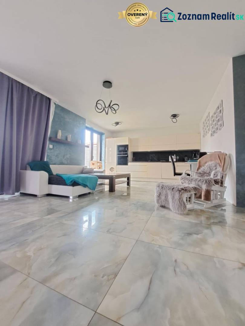 Wohnzimmer mit großen Fenstern und hellen Fliesen in einem Einfamilienhaus.