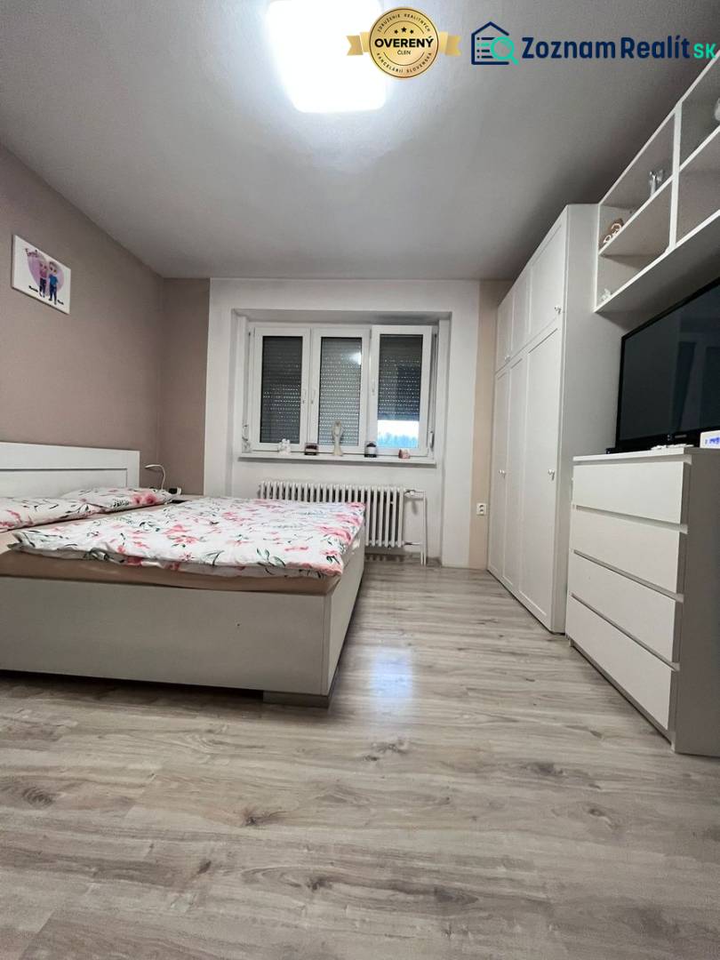 Helles Schlafzimmer in einem Einfamilienhaus mit Bett, Kleiderschrank und Boden in Holzoptik.