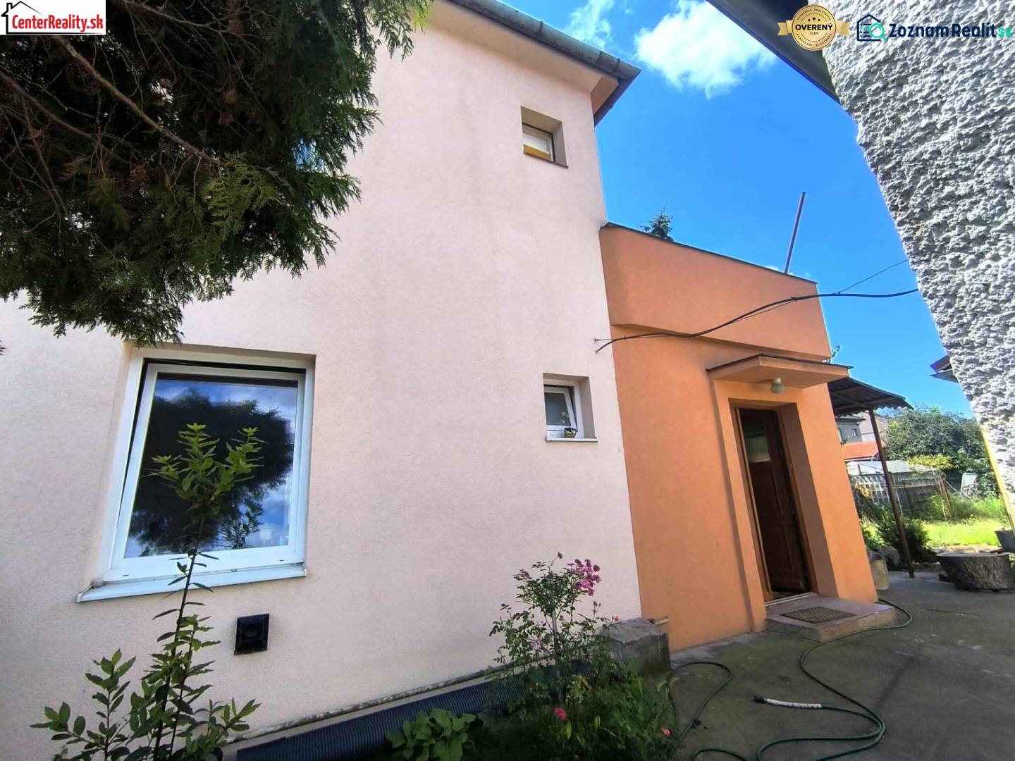 Das Einfamilienhaus in Partizánske hat eine rosa Fassade, kleine Fenster und eine Eingangstür.