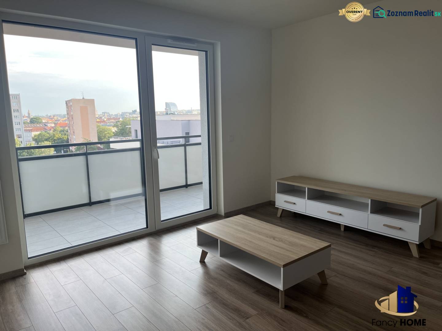 Wohnzimmer in einer Zweizimmerwohnung mit Holzboden und großem Balkonfenster.