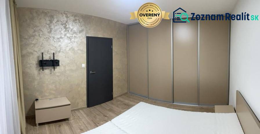 Schlafzimmer in einer Einzimmerwohnung mit Holzboden, Einbauschrank und TV-Halterung.