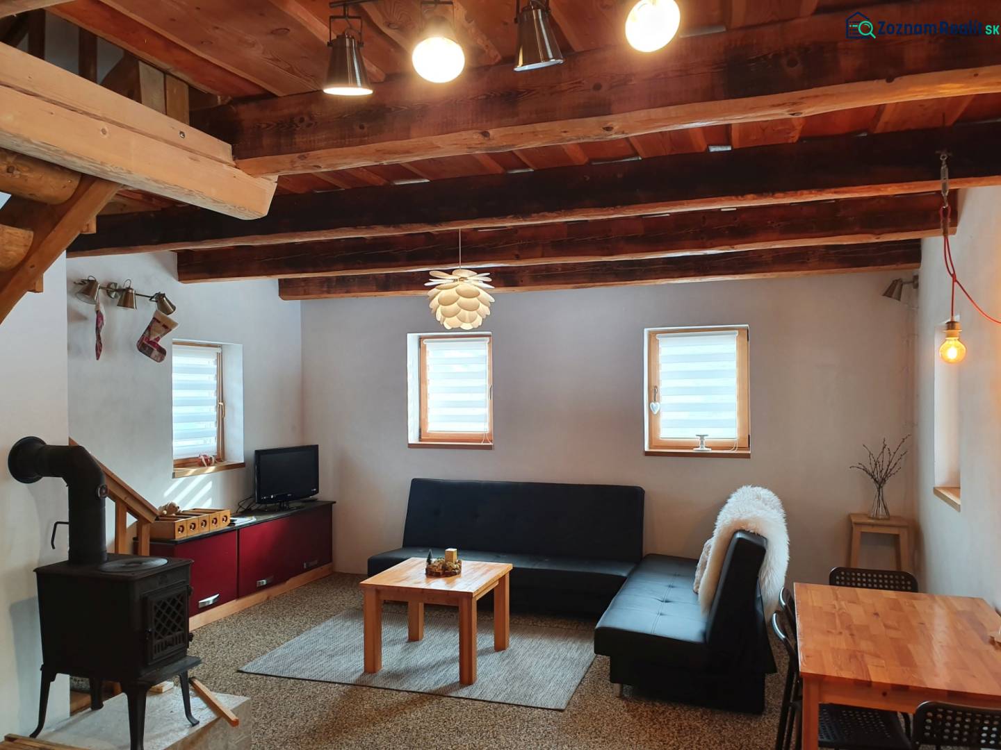 Das Innere der Hütte mit einem Kachelofen, einem Sofa und einer Holzdecke aus massiven Balken.