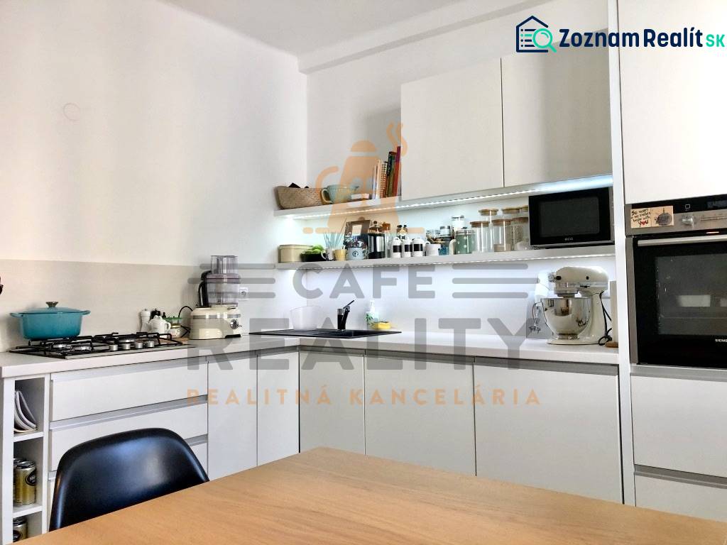 Küche in einer 2-Zimmer-Wohnung mit weißen Schränken und eingebauten Geräten.