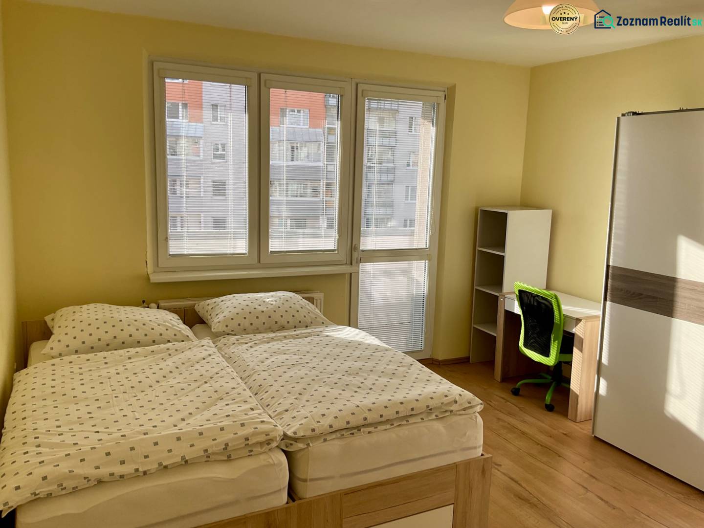 Schlafzimmer mit Doppelbett, Schreibtisch und Boden mit Holzdekor in einer 3-Zimmer-Wohnung.