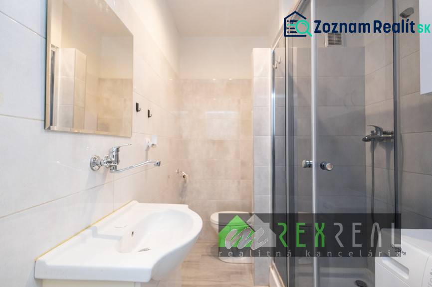 Badezimmer in einer 3-Zimmer-Wohnung mit Duschkabine, Waschbecken und hellen Fliesen.