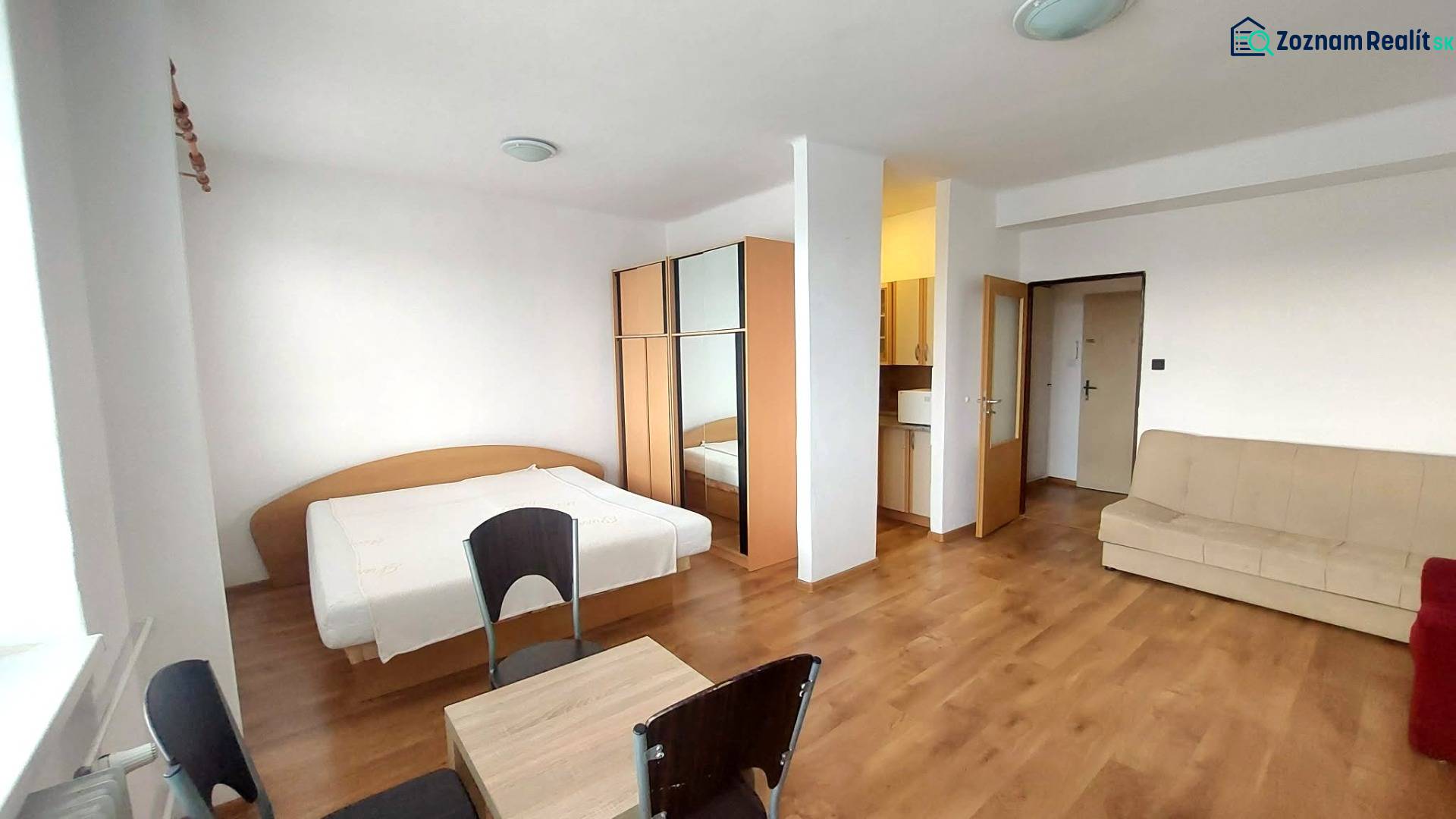 Einzimmerwohnung mit Holzboden, Bett, Sofa und Schrank.