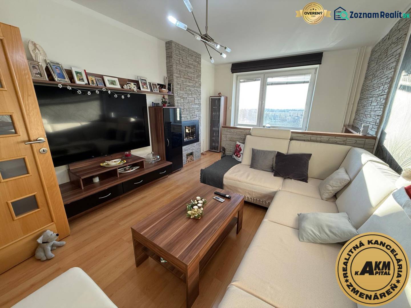 Wohnzimmer in einer 3-Zimmer-Wohnung mit komfortablem Sofa, Holzboden und Fernseher.