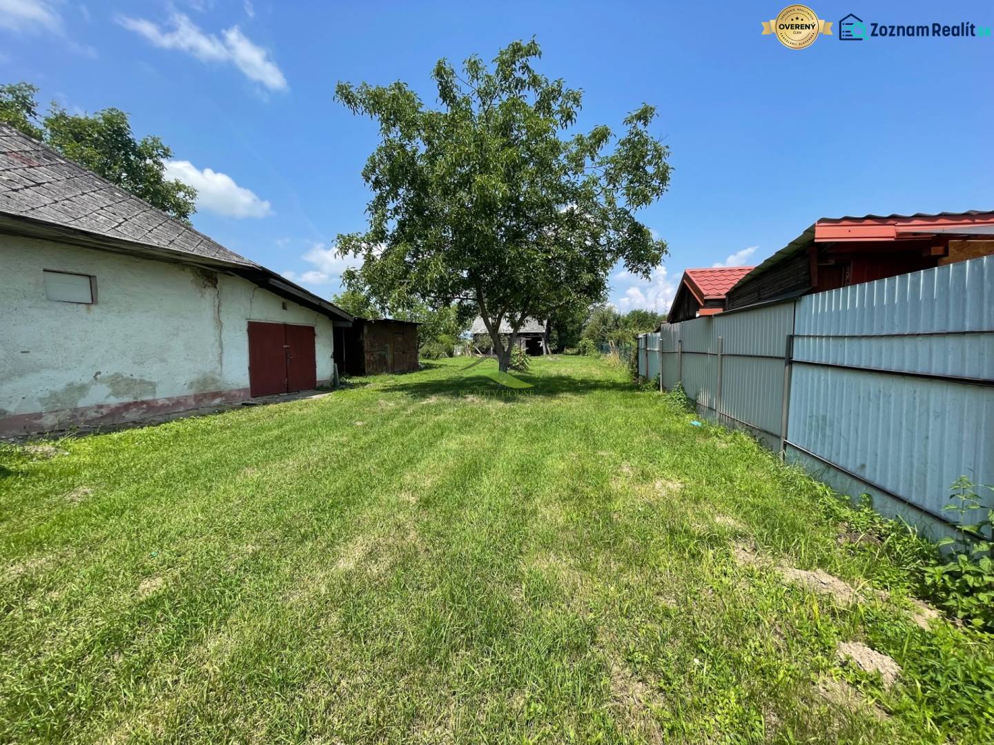 Blick auf ein grünes Grundstück in Zemplínska Široká, ideal zum Wohnen, mit sichtbaren Gebäuden.
