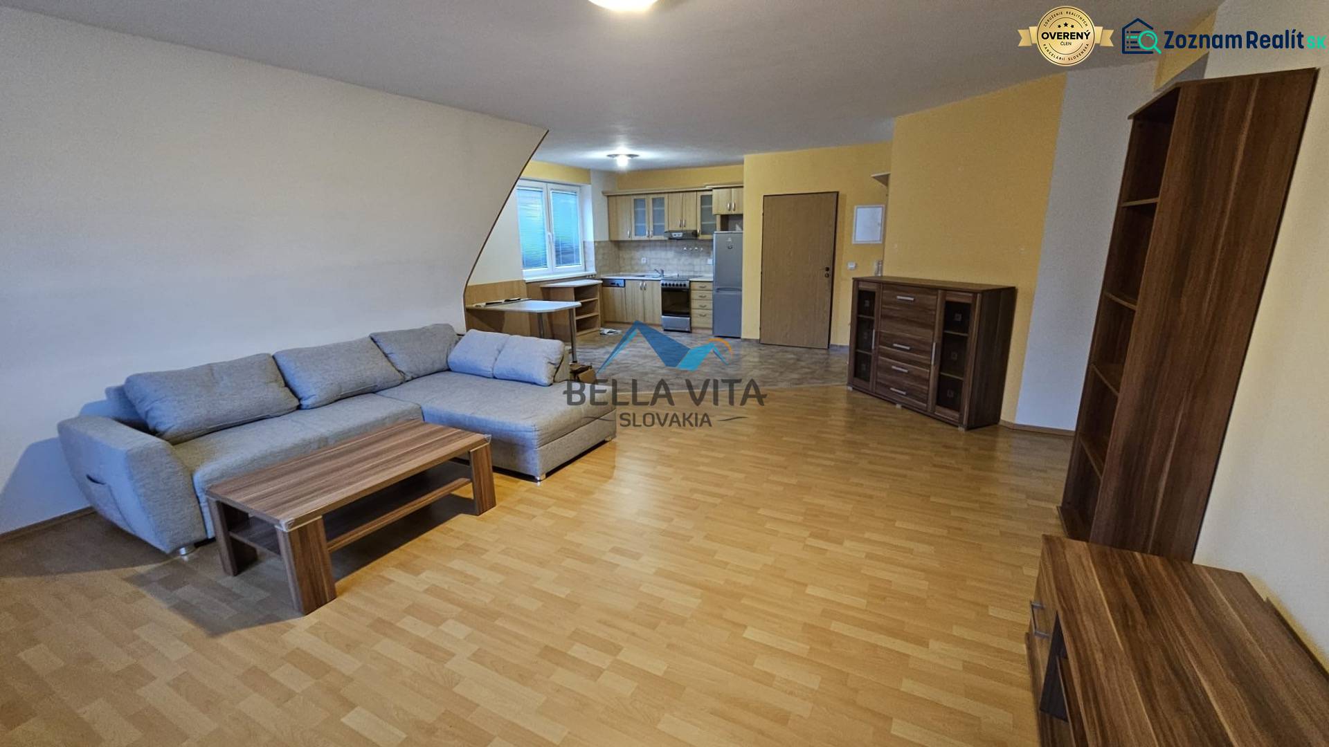 Ein Interieur mit einem Sofa, einer Küche und einem Holzboden in einem Gebäude.