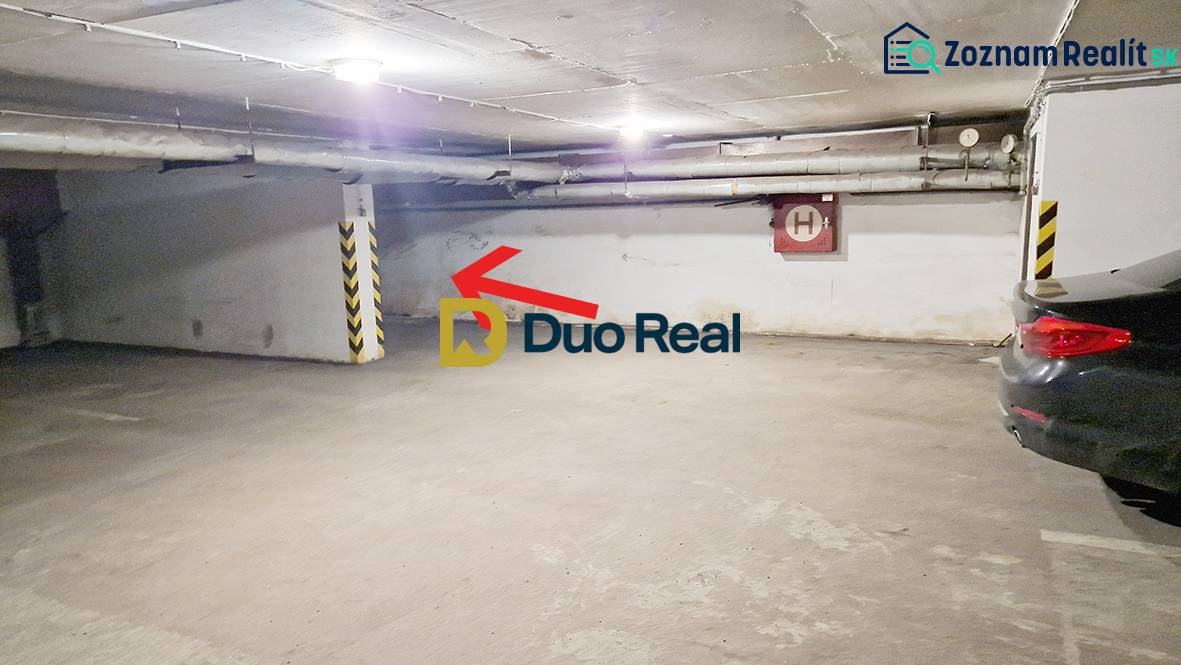 Unterirdischer Parkplatz in der Garage mit einem Stellplatz an der Wand und Autos.