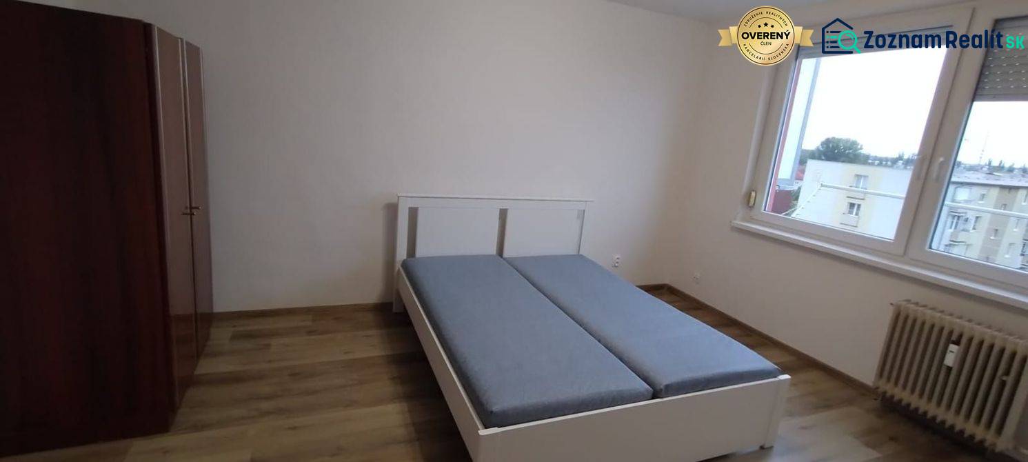 Schlafzimmer in einer Einzimmerwohnung mit Bett, Schrank und Boden in Holzoptik.