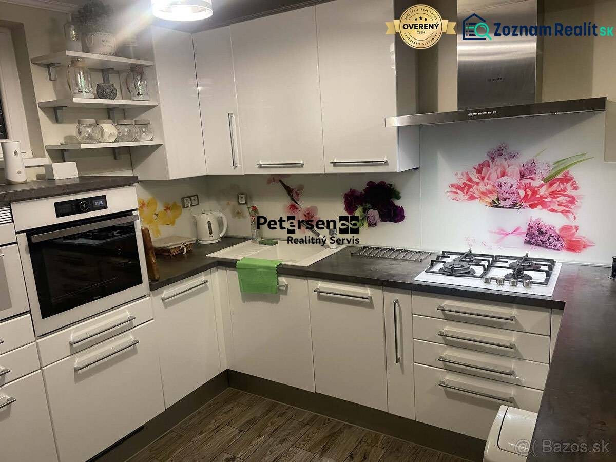 Küche in einem Einfamilienhaus mit weißen Schränken, dekorativen Fliesen und einem Boden mit Holzdekor.