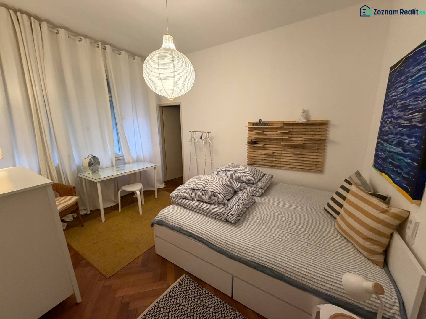 Schlafzimmer in einer 2-Zimmer-Wohnung mit Holzboden und minimalistischer Einrichtung.