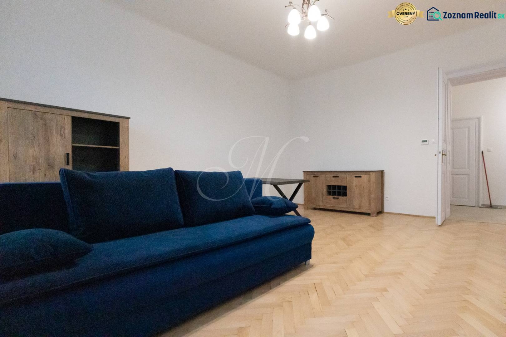 Ein Zimmer mit einem blauen Sofa und Holzboden-Dekor in einer 3-Zimmer-Wohnung.