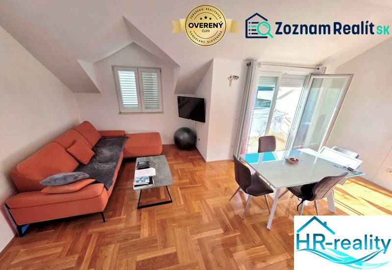 Das Ferienapartment bietet ein Sofa, einen Esstisch und einen Boden mit Holzdekor.