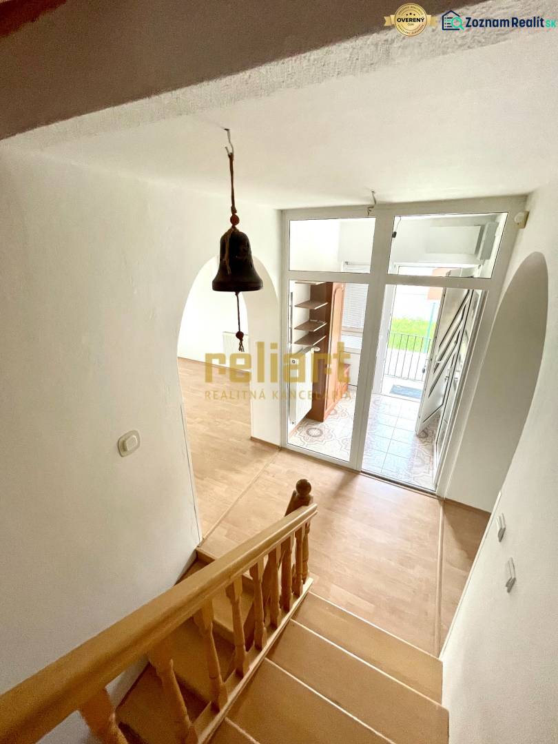 Treppe mit Holzboden, Eingangstür und Türklingel in einem Einfamilienhaus.