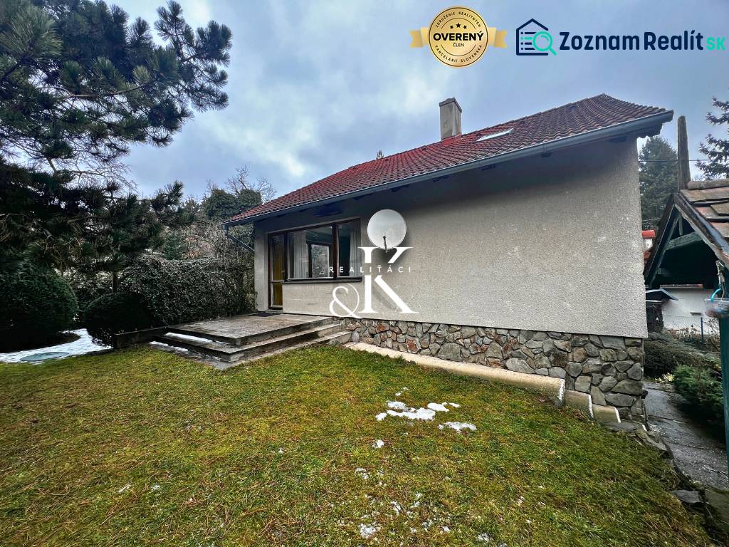 Hütte bei Modra mit einer Rasenfläche, Steintreppen und Nadelbäumen.