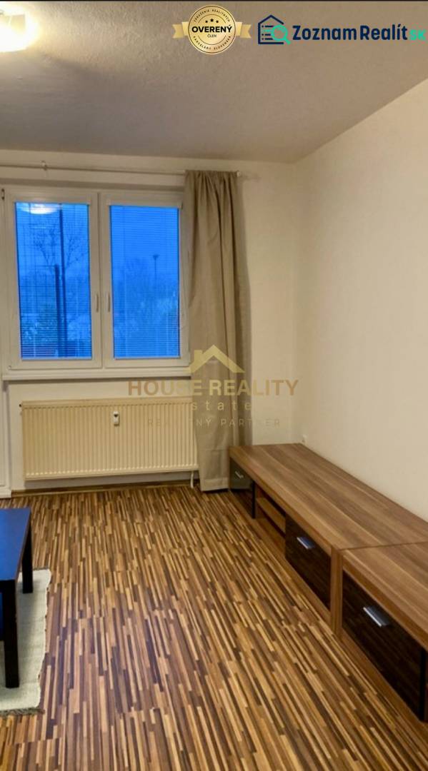 Wohnzimmer in einer 3-Zimmer-Wohnung mit Holzboden und Blick durch ein großes Fenster.