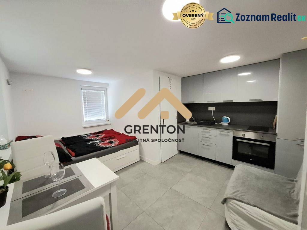 Küchenecke und Bett in einer Hütte mit grauer Verkleidung und Ausstattung.