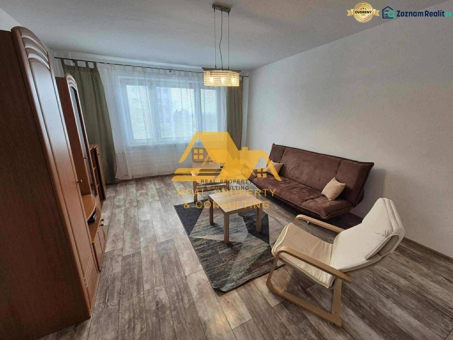 Wohnzimmer in einer 3-Zimmer-Wohnung mit Sofa, Sessel und Boden in Holzoptik.