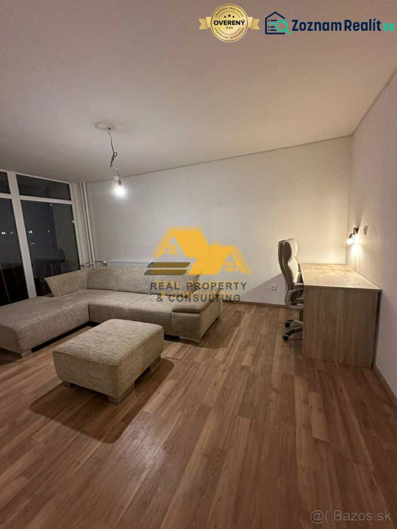 Wohnzimmer einer Zweizimmerwohnung mit Holzboden, Ecksofa und Tisch.