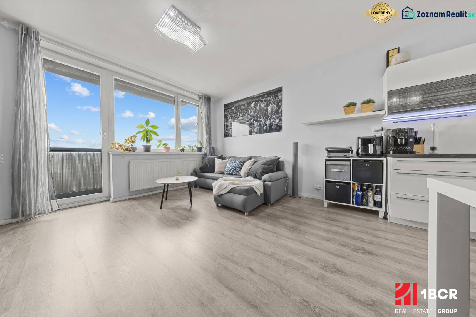 Wohnbereich einer 2-Zimmer-Wohnung mit Sofa, Tisch und Boden in Holzoptik.