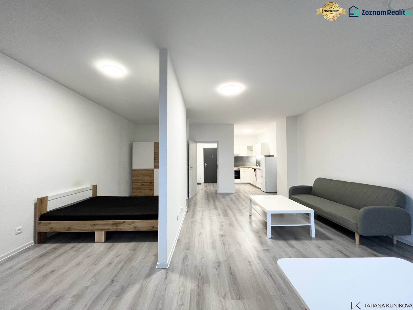 Innenraum einer Einzimmerwohnung mit Holzboden, Bett und Sofa.