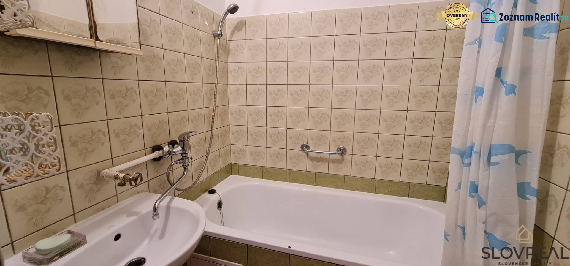 Ein Badezimmer mit Spiegel und Badewanne in einer 3-Zimmer-Wohnung, gefliest mit dekorativen Fliesen.