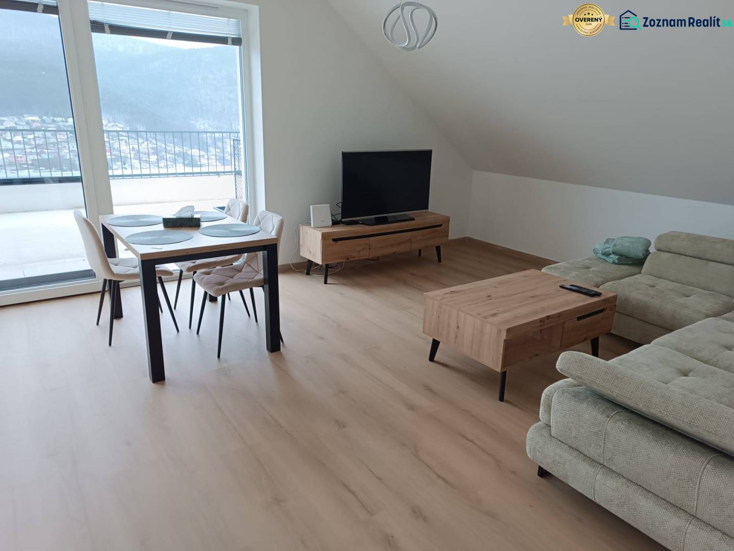 Wohnzimmer in einer Zweizimmerwohnung mit Holzboden, Esstisch und Sofa.