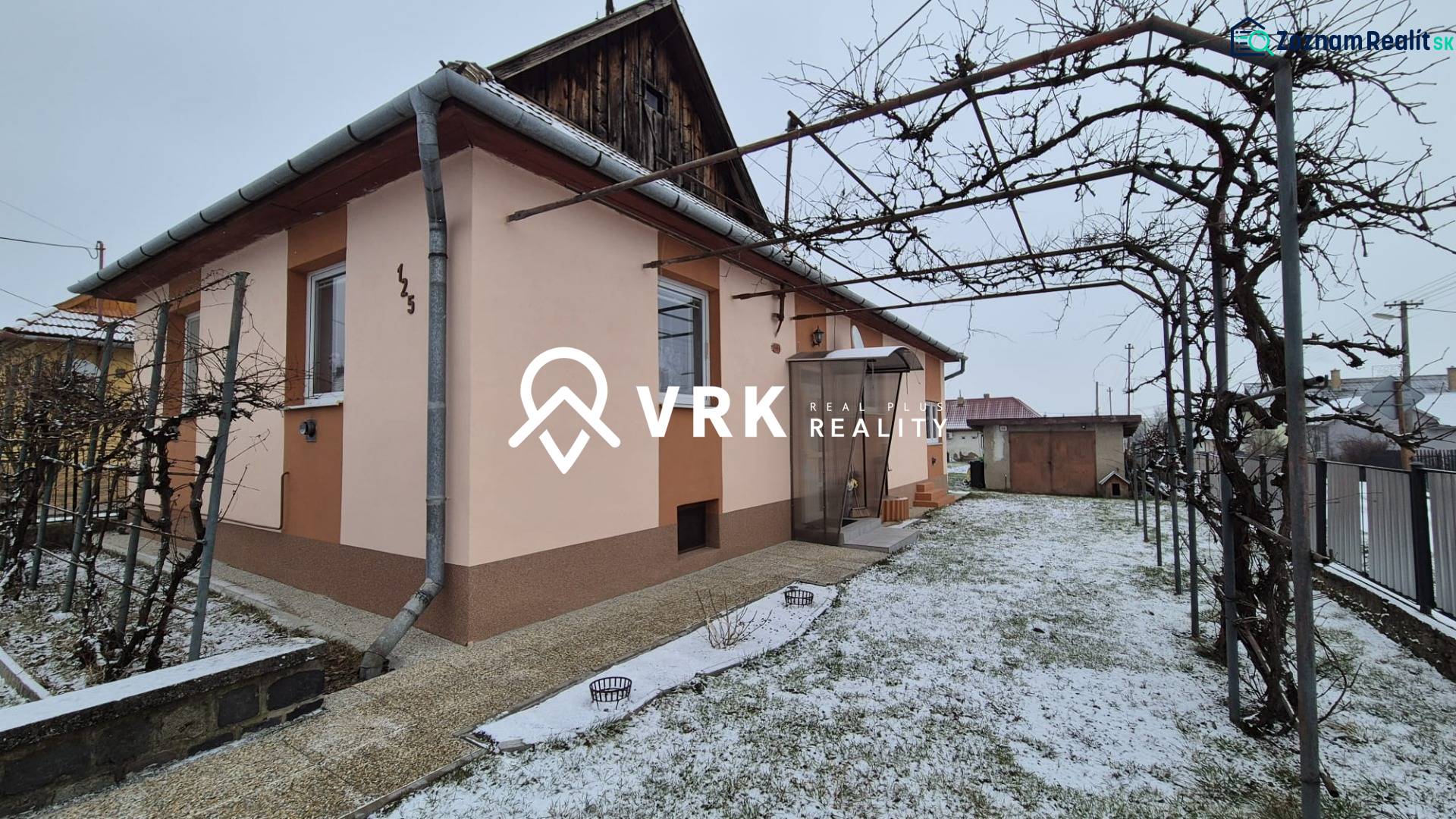 Ein Einfamilienhaus in der Neuen Straße in Veľké Ozorovce mit einem Rohrpavillon und einem verschneiten Garten.