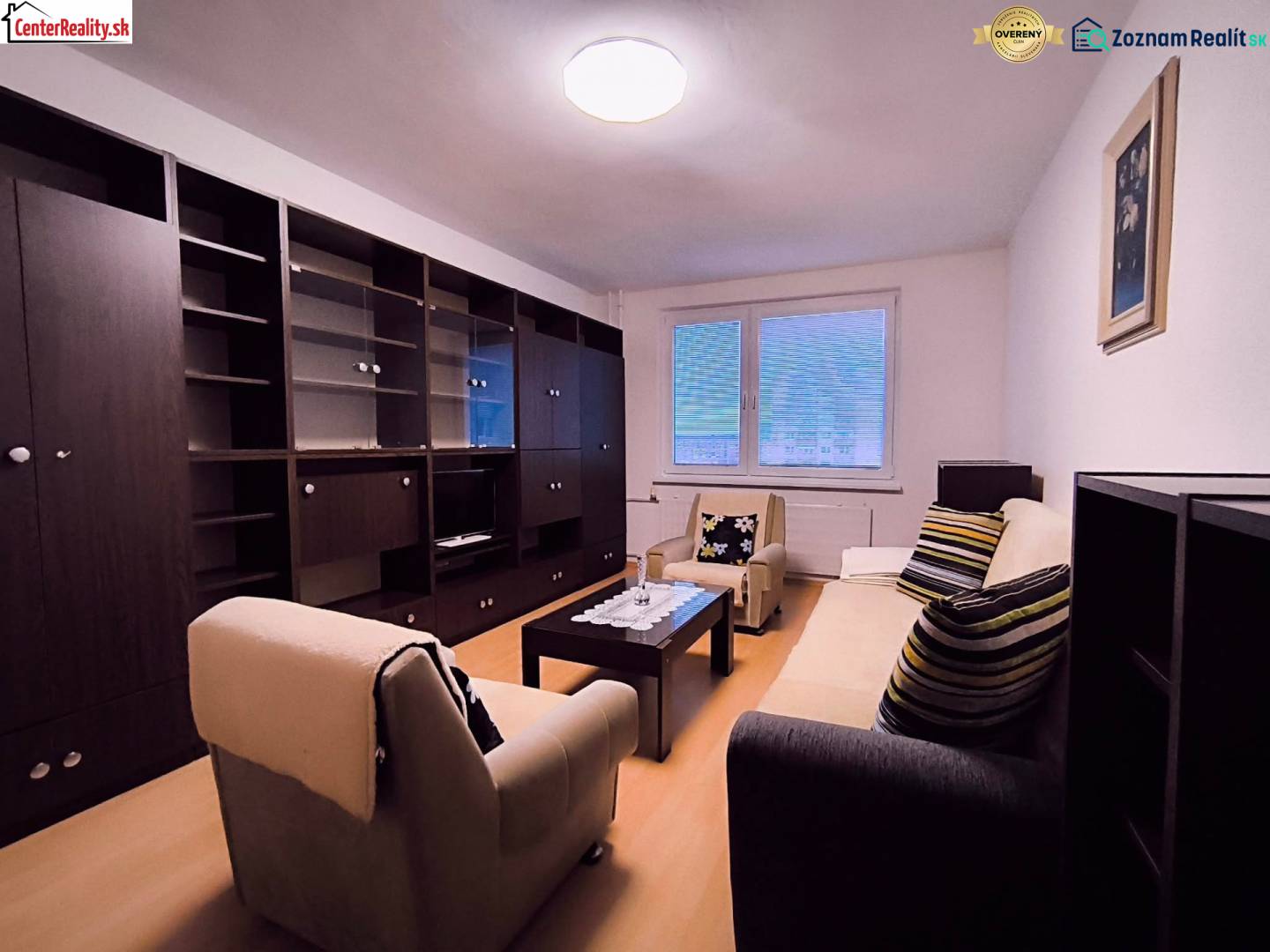 Wohnzimmer mit Sofa, Sesseln, Couchtisch und Wohnwand in einer Zweizimmerwohnung.