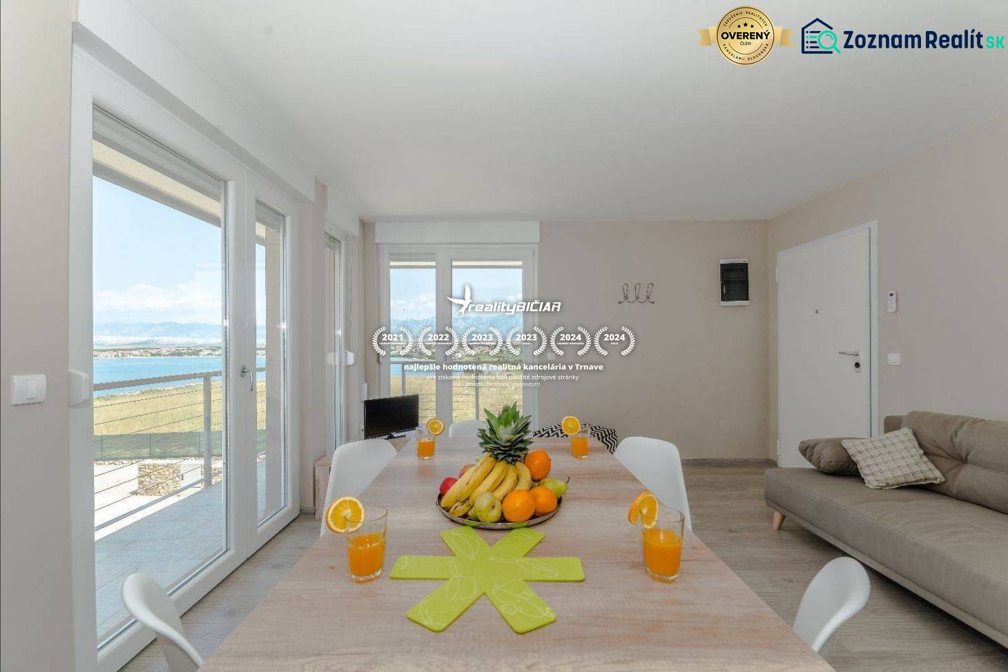 Esstisch im Ferienapartment mit Meerblick durch große Fenster.