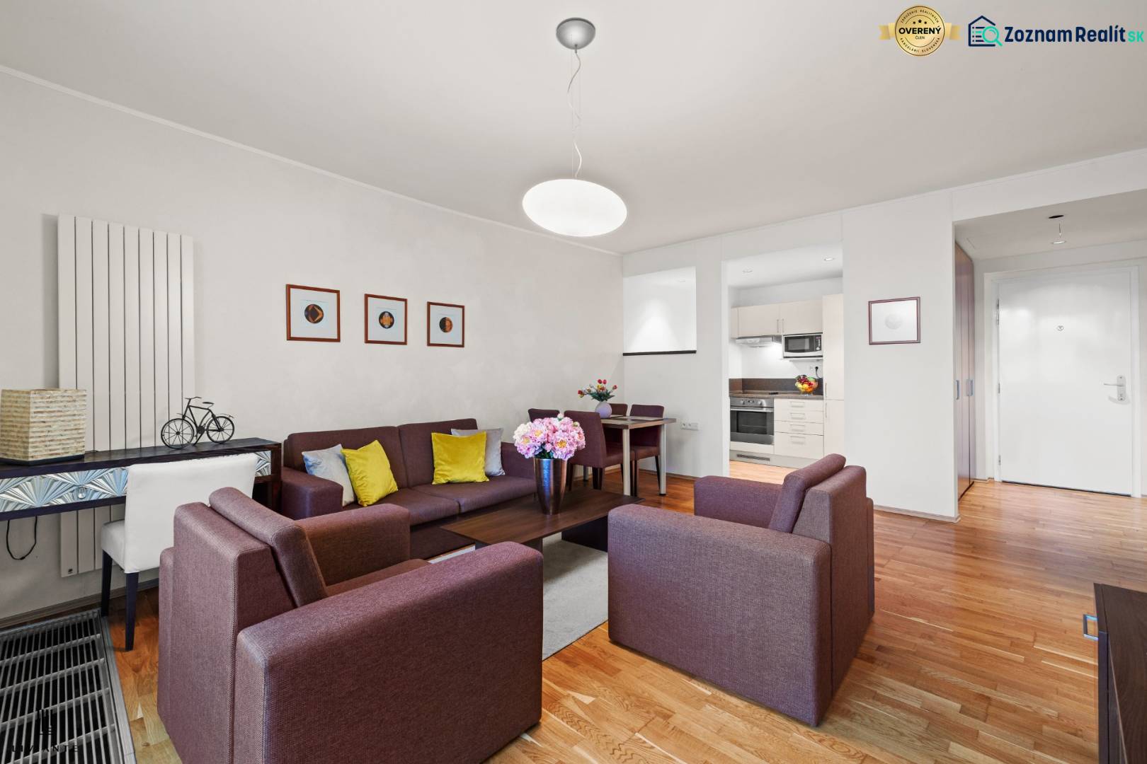 Wohnzimmer in einer 2-Zimmer-Wohnung mit Holzboden, bequemen Sofas und einer Kochnische.